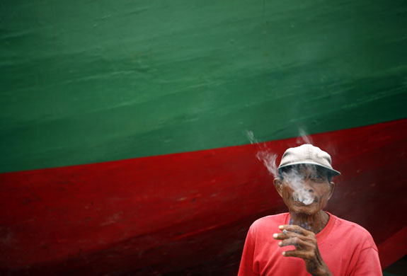 Gallery 14 January 2009: A man smoke a cigarette near a traditional schooner at Sunda Kelapa port