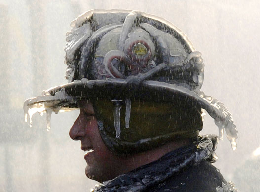 Gallery 24 hours in pictures : A firefighter is coated with ice after fighting a fire 