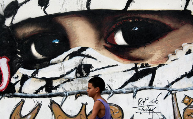 Gallery 24 hours in pictures: A young Venezuelan boy walks past a grafitti depicting a Palestinian boy