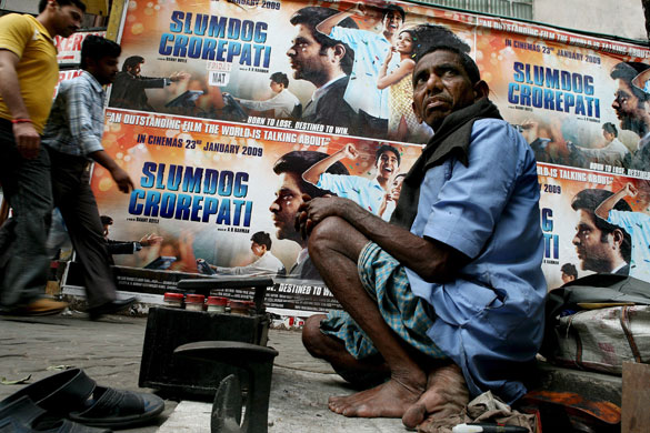 Gallery 23 January 2009: Kolkata, India: A shoe maker next to a Slumdog Millionaire film poster