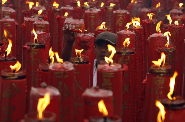Gallery World Chinese New Year: A man lights candles in a temple