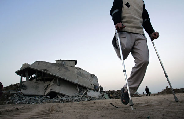 Gallery 30 January 2009: Jabalya, Gaza Strip: A man uses crutches as he walks near rubble of houses
