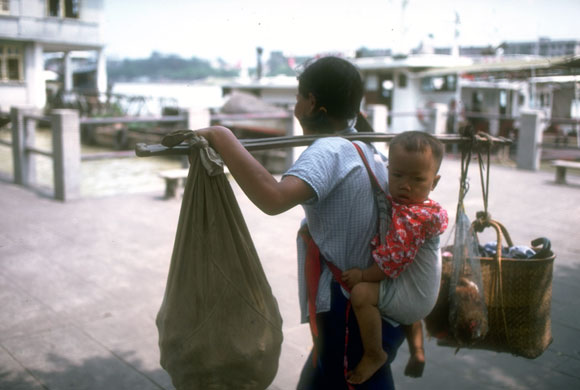 Gallery China then and now: A woman carries her toddler in a baby sack and the family's food shopping