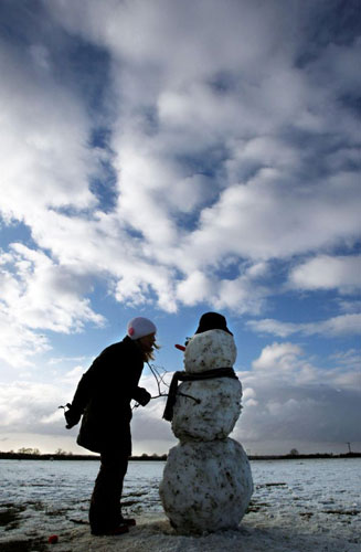 Gallery Snow: Cambridge, UK: Emily Rhodes puts a hat on a snowman near her home