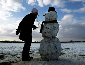 Emily Rhodes puts a hat on a snowman near her home in Cambridge