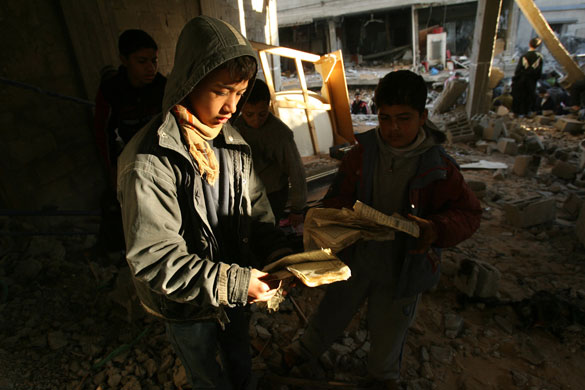 Gallery Gaza: Palestinian boys pick up pages from a torn Koran