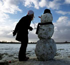 Emily Rhodes puts a hat on a snowman near her home in Cambridge