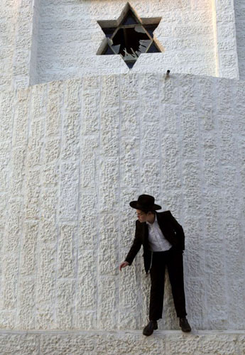 Gallery 6 January 2009: An ultra-Orthodox Jewish youth stands under a window that was shattered