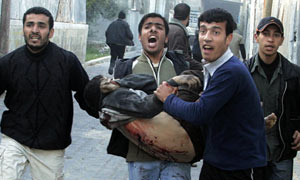 A wounded Palestinian is carried near United Nations school in Jabalya