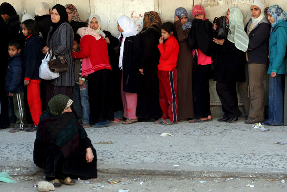 Gallery Gaza: Palestinians wait in line to buy bread outside a bakery in Gaza City  