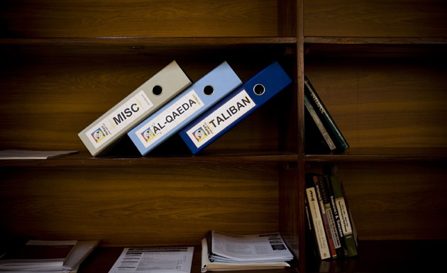 Gallery Soldier standing guard: Folders labled Taliban, Al-Qaeda and Misc on a shelf