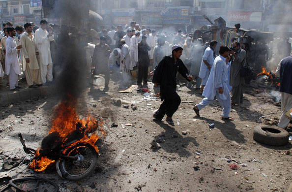 Pakistan: 9 October 2009: Men walk past the aftermath of a car-bomb explosion