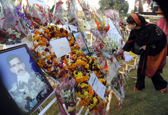 Pakistan: 12 October 2009: A woman places flowers next to portraits of army soldiers