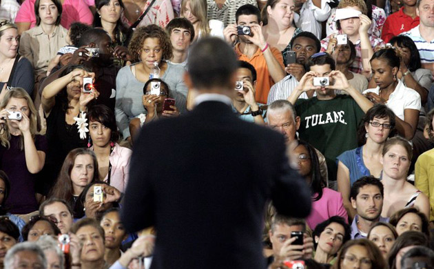 Attendees of a town hall meeting at the University of New Orleans take pictures of Barack Obama