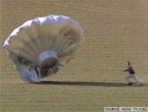 Balloon boy: A law enforcement officer runs toward the balloon as it lands