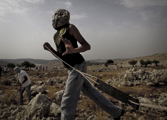 24 hours in pictures: A Palestinian demonstrator uses a sling to throw stones at Israeli soldiers