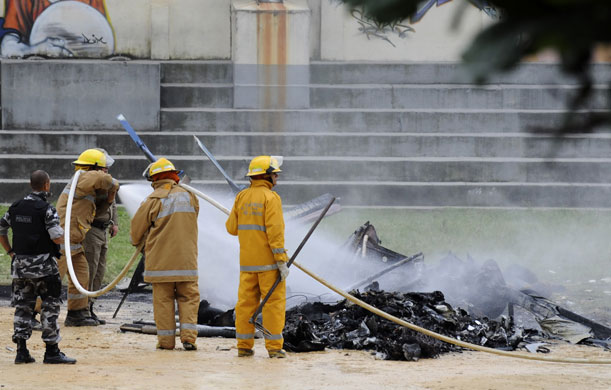 Rio de Janeiro: Firefighters throw water to the remains of a police helicopter