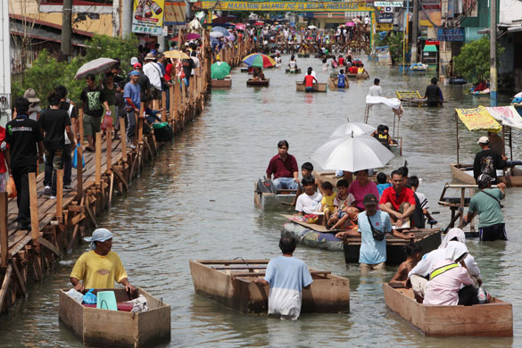 Philippines flooding: 16 October 2009: People use a makeshift bridge and floating rafts