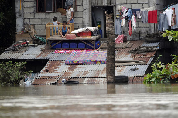 Philippines flooding: 12 October 2009: Children on the roof of a house in the town of Calumpit