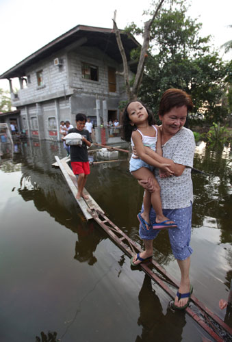 Philippines flooding: 12 October 2009: People use makeshift bridges to leave their house