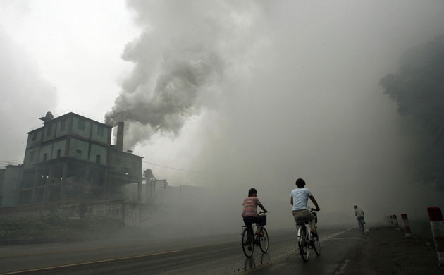 Environment decade: Cyclists pass through thick pollution from a factory in Yutian China
