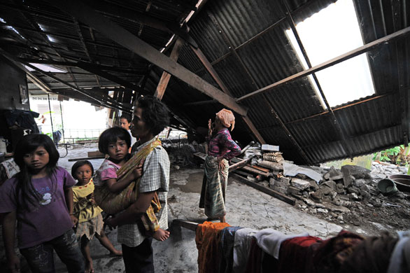2 October 2009: Padang, Sumatra: Residents inspect the wreckage of their home