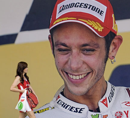 24sport: A woman walks near a poster of MotoGP poster of Italian Valentino Rossi