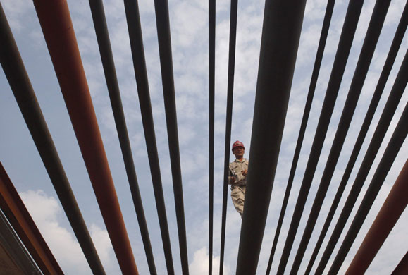 Week in Business: A worker walks on oil pipes at a refinery in Suining