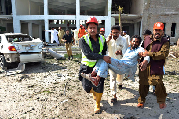 more bombings in pakistan: Pakistani rescuers help an injured man at a bomb blast site in Peshawar