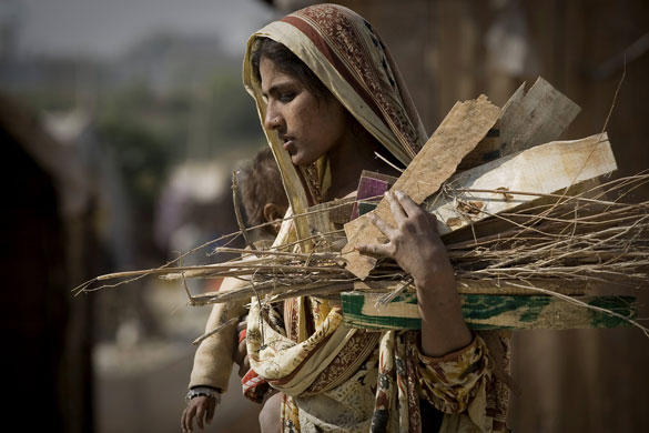 24 hours: A woman holds a baby and firewood as she walks in a slum in Rawalpindi