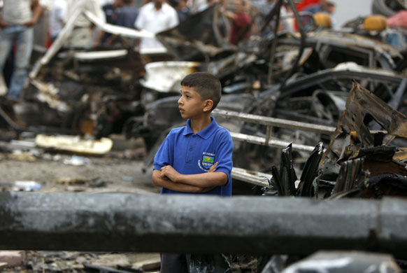 Bomb in Baghdad: An Iraqi boy stands amongst the debris of destroyed vehicles