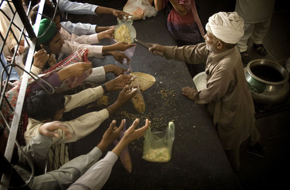 Environment decade: Men hold plastic bags for food distribution at a mosque in Lahore, Pakistan