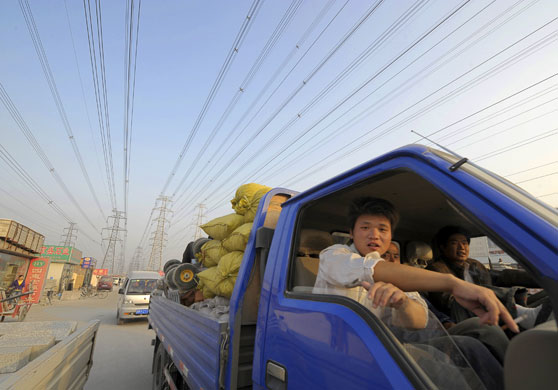 24 hours in pictures: Beijing, China: Men riding a truck pass beneath overhead power lines