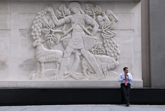 Week in business: A city worker sits under a giant sculpture in London's financial district
