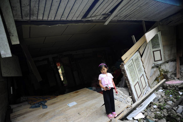 24 hours: A young girl stands in her destroyed house in Sumatra