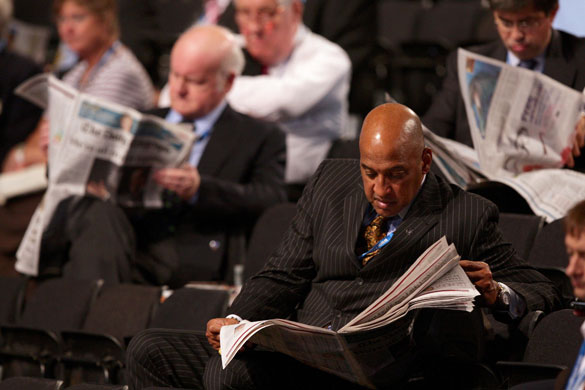 Conservative conference 3: Delegates read newspapers as Theresa May takes part in a panel discussion 