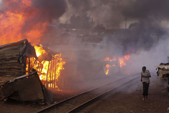 runs past burning shacks during ethnic riots in the Kibera shanty town