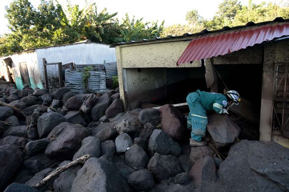El Salvador hurricane: A rescue worker looks into a damaged house in the village of Verapaz