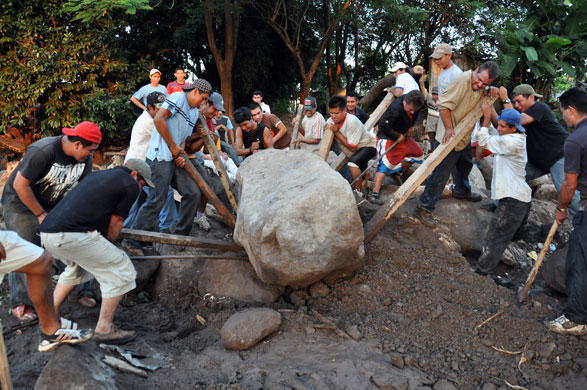 El Salvador hurricane: Men try to move a rock following a landslide of mud and rocks in Verapaz