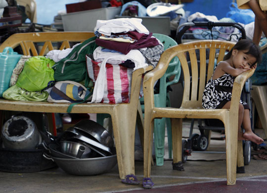 24 hours: A child waits for her parents as they collect food rationsin Manila