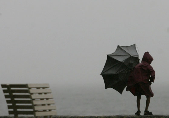 24 hours: Mumbai, India: A boy tries to hold on to an umbrella at a seafront