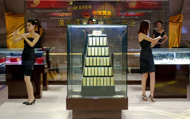 Week in Business: Promotions girls show off gold bars at an exhibition in Beijing, China