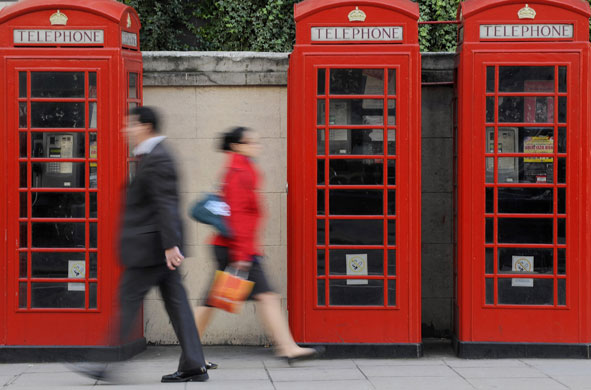 Week in Business: Pedestrians walk past telephone boxes in central London