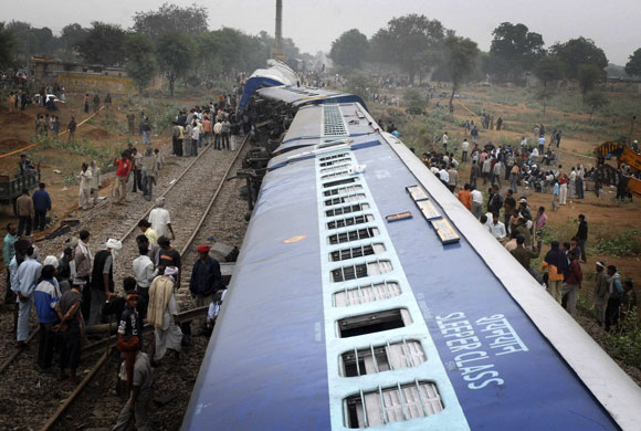 24 Hours in Pix: Onlookers stand beside derailed carriages of a passenger train in India