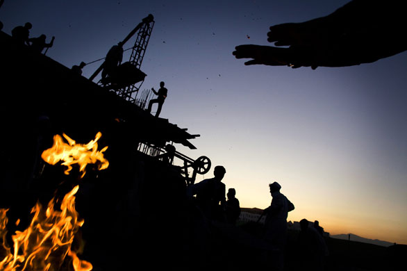 24 Hours in Pix: An Afghan worker warms his hands over a fire at a construction site