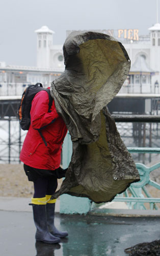 UK gales: A woman's poncho blows over her head as she walks on Brighton seafront