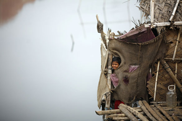 17 November 2009: Dhaka, Bangladesh: A boy looks out from a his makeshift house