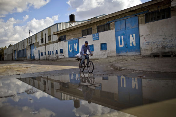 17 November 2009: Gaza Strip: A man rides a bicycle in front of a UN food distribution centre