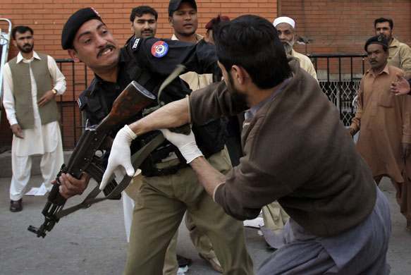 Pakistan bombing: A policeman tries to control a rescue worker who started fighting