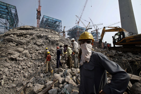 Week in Business: Rescue workers look on near the debris of a fallen chimney